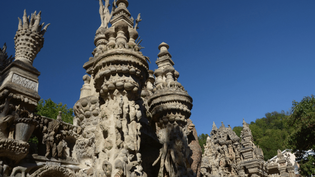 Vista lateral do Palais Idéal com esculturas, colunas e relevos em toda a estrutura.