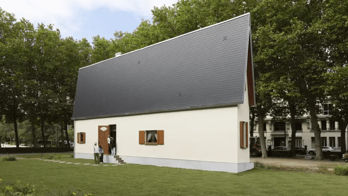 Casa em formato triangular com fachada baixa e telhado inclinado.