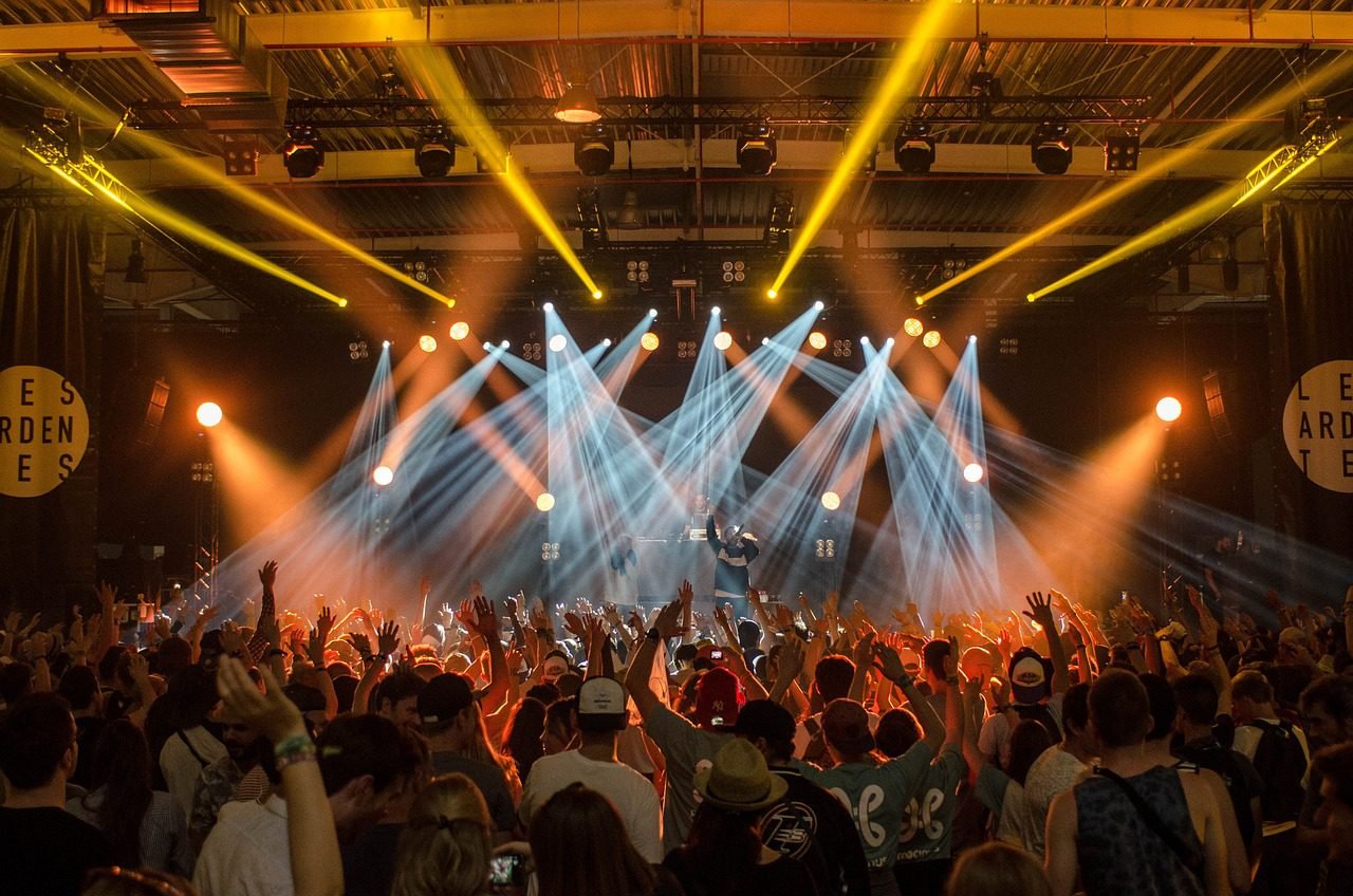 Palco iluminado com público em evento de inovação e música