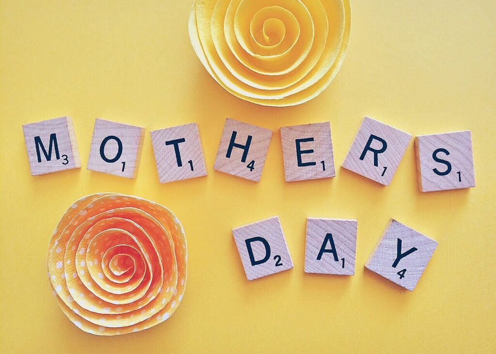 Letras decorativas com a frase Mothers Day e flores ao fundo